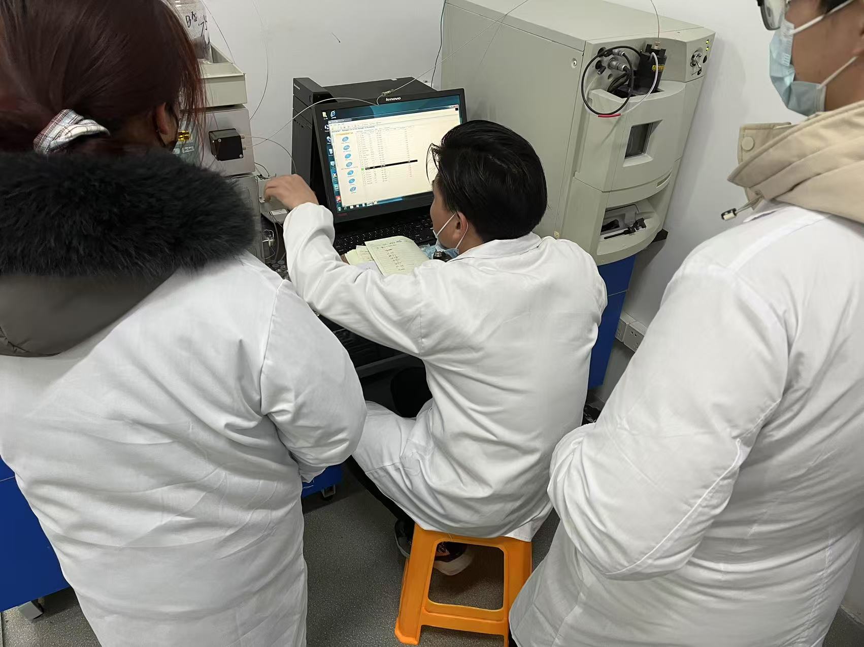 Laboratory team gathered at an instrument in supplied project materials